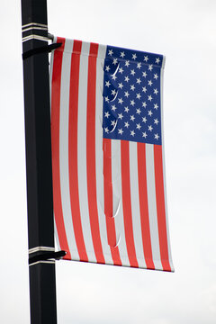 ripped American flag on a black pole 