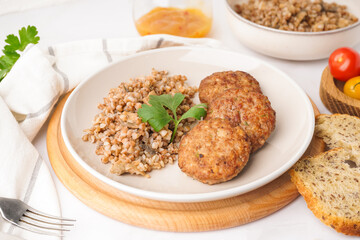 Cutlets with buckwheat, mushrooms and parsley on white table in kitchen