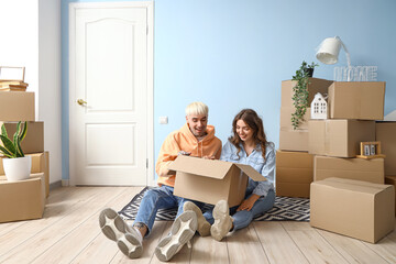 Fototapeta na wymiar Young couple with box in room on moving day