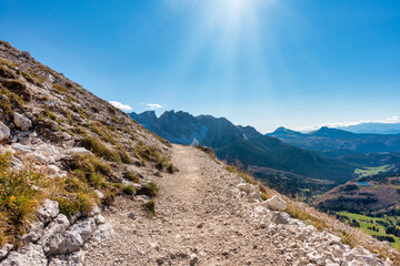 Alpine hiking trail in dolomites mountains against blue sky with view over peaks