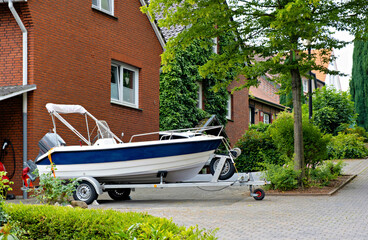 Blue and white boat parked in front of red brick building with white roof.