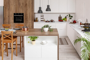 Interior of modern kitchen with island table and white counters