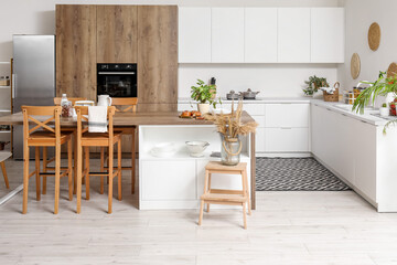 Interior of light kitchen with white counters, island and integrated oven