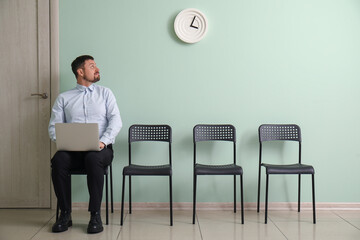 Male applicant with laptop waiting for job interview in room