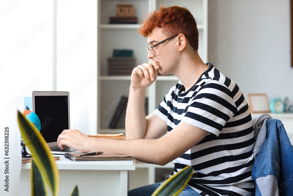 Canvas Prints Young redhead man studying with laptop at home