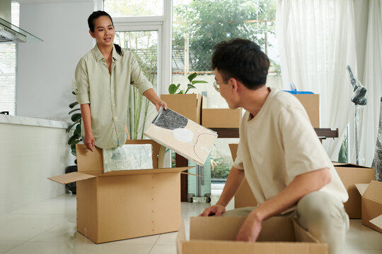 Married Asian couple unpacking pictures in new apartment - Powered by Adobe