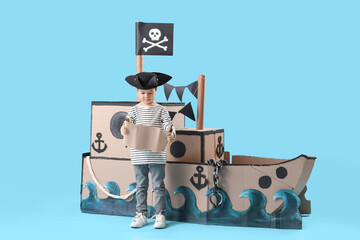 Cute little pirate with treasure map and cardboard ship on blue background