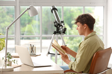 Young man with telescope and notebook at table