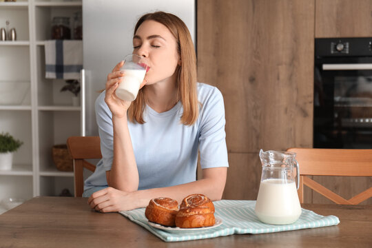 Young woman drinking milk in kitchen