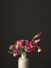 Flowers Still life. Beautiful pink flowers in vase in light on moody grey background. Stylish artistic composition of snapdragon, roses, ranunculus,gladiolus. Floral vertical wallpaper