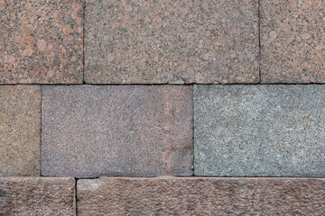 Wall of granite blocks. Rough surface of rock with a grainy pattern. Stone wall in classic style....
