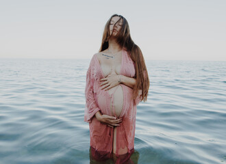 Pregnant woman in the sea holding her belly