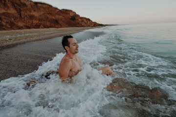 Happy man sitting in the sea waves