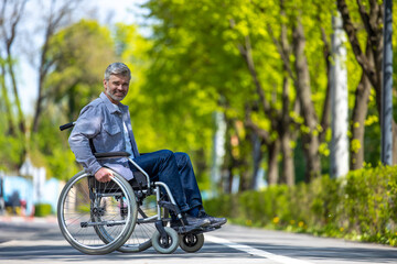 Handicapped man in wheelchair riding on street road, outdoor leisure for disable guy.