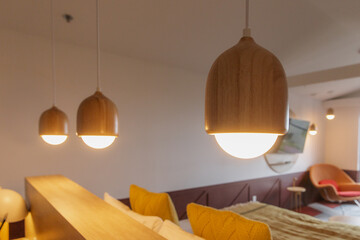 vue sur trois lampes suspendues au plafond en bois dans une pièce aux murs blancs avec la lumière allumée 