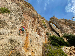 LOW ANGLE VIEW: Female rock climber in the middle of a beautiful climbing route