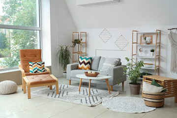 Interior of light living room with plants, sofa and armchair