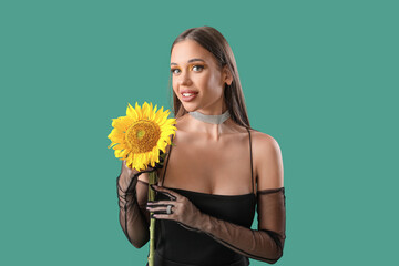 Elegant happy young woman with beautiful sunflower on green background