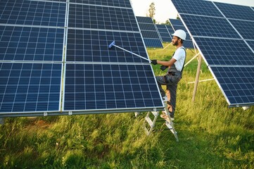 Indian man in uniform working near solar panel.