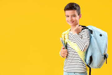 Portrait of happy schoolboy with backpack on orange background