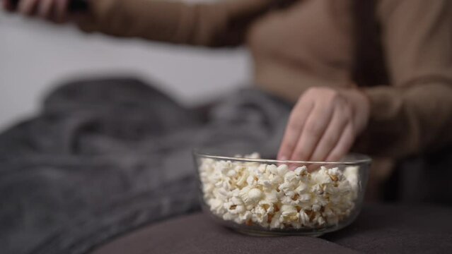 Close up asian woman watching movie on tv and eating popcorn at night.
