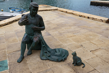 Bronze sculpture of fisherman and cat in Spinola Bay, St Julian's Bay, Malta