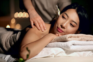Obraz na płótnie Canvas Pretty young Asian woman having massage in spa salon