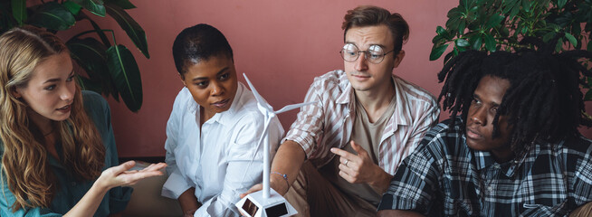 Diverse group of international students working on the urban project of modern city with renewable energy source, green areas. Concept of ecology, environment, waste recycling, technology. Banner