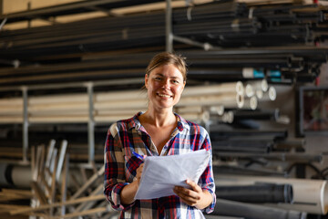 Obraz premium Portrait of positive caucasian woman working in warehouse, checking documentation.