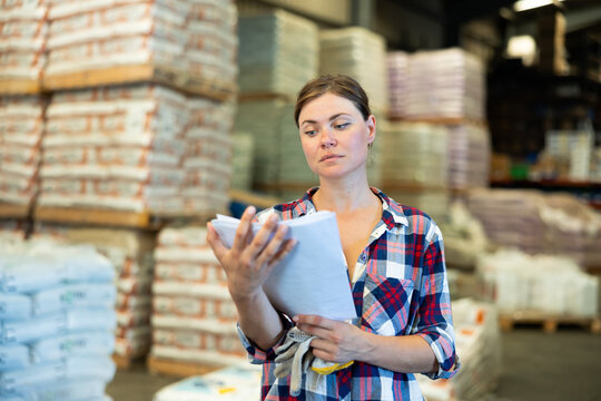 Portrait of caucasian woman working in warehouse, checking documentation.