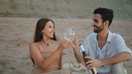 Smiling couple clinking wine glasses beach picnic. Family celebrating honeymoon