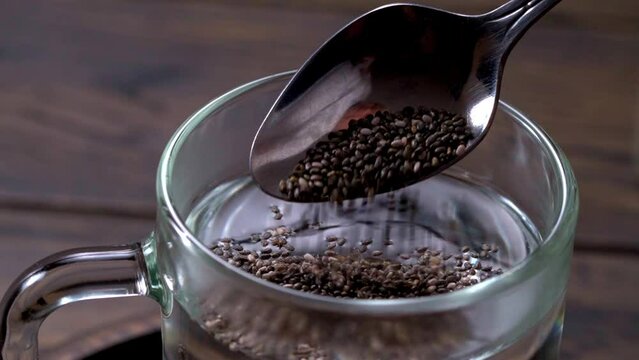 Pouring chia seeds into warm water. Preparation of chia seeds water