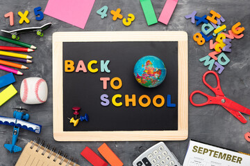 Obraz premium Globe and the inscription BACK TO SCHOOL on the school board. Pencils, letters and stationery on a gray background. view from above.