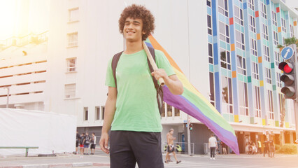Smiling handsome young man with LGBT flag in his hands