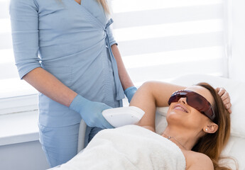 Cosmetology session of laser hair removal at a meeting with beauty. The woman's body shone with new brilliance thanks to a visit to a beauty clinic. The work of a professional cosmetologist - obrazy, fototapety, plakaty