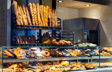 Interior of small Spanish bakery shop with racks and showcase full of pastries and baked goods
