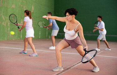 Latin woman serving ball during frontenis game outdoors. Woman playing pelota on outdoor fronton.