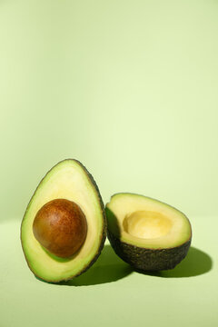 avocado cut in half on a table with green background