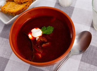 Just prepared portion of red beetroot soup, svekolnik, served on table with parsley and smetana. Russian soup with smetana.