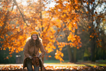 smiling elegant female throws up autumn leaves
