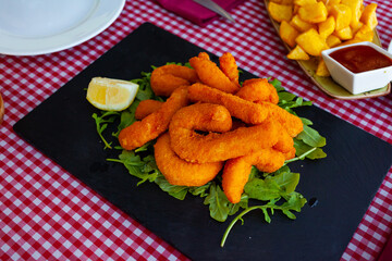 Dish of tasty fried sepia in a batter of tempera flour served with arugula and lemon