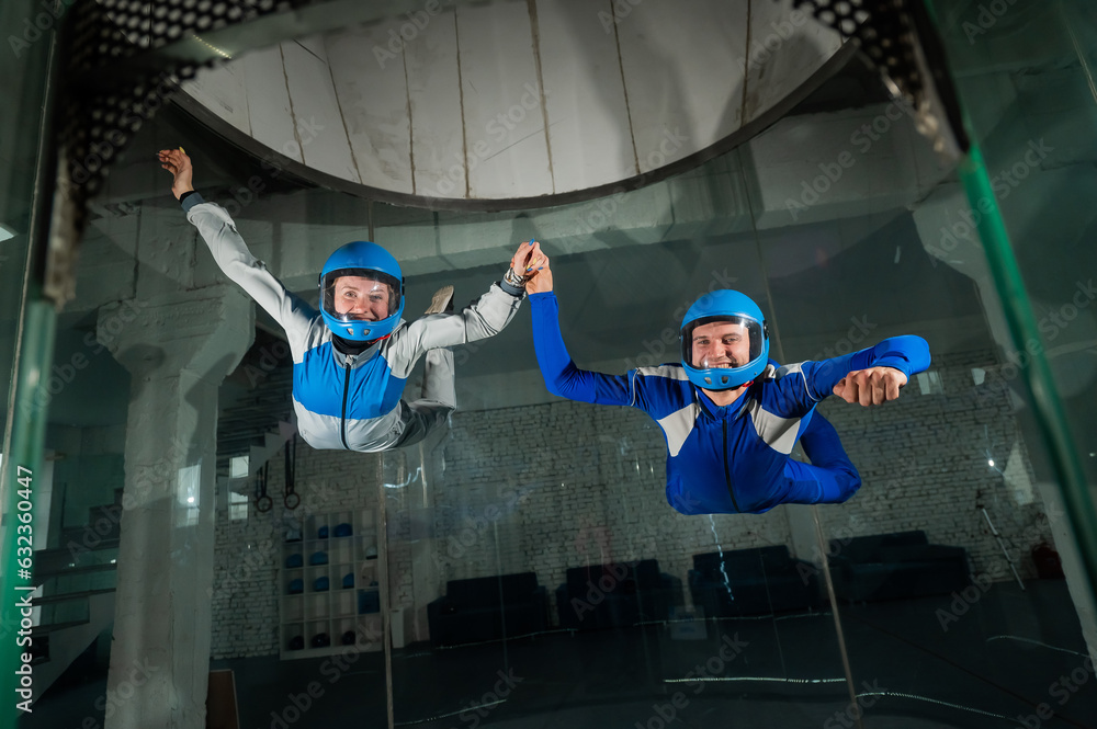 Wall mural a man and a woman enjoy flying together in a wind tunnel. free fall simulator