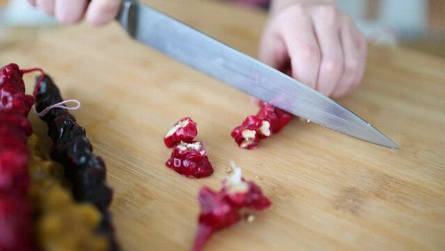 Close-up view of female hands cutting Georgian churchkhela candy into pieces