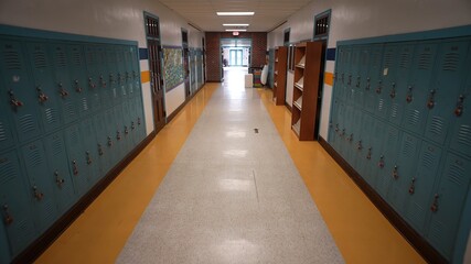 High angle slow motion push in down a long empty high school corridor hallway.