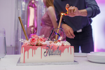 Ręka podpalająca tort urodzinowy. Tort urodzinowy. Tort na 18-stkę. 18 urodziny. Różowy tort....