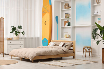 SUP board, bed and furniture in room. Interior design