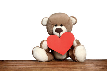 Cute teddy bear with red heart on wooden table against white background