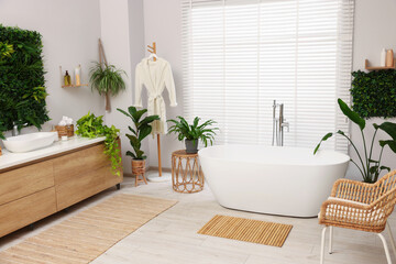 Green artificial plants, vanity and tub in bathroom