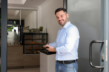 Happy business owner inviting to come into his cafe. Space for text