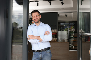 Happy business owner at door of his cafe. Space for text